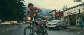 Movie still from “First Blood” (1982), directed by Ted Kotcheff – A man riding a motorcycle down a street; Wide shot, Low angle