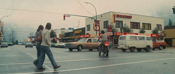 Movie still from “First Blood” (1982), directed by Ted Kotcheff – A man riding a bike down a street next to a traffic light; Extreme Wide shot, Low angle