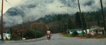 Movie still from “First Blood” (1982), directed by Ted Kotcheff – A person riding a motorcycle down a street; Extreme Wide shot, Low angle