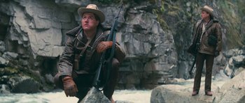 Movie still from “First Blood” (1982), directed by Ted Kotcheff – A man sitting on some rocks holding a rifle; Medium shot, Low angle