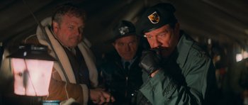 Movie still from “First Blood” (1982), directed by Ted Kotcheff – A group of men standing next to each other in a dark room; Medium shot, Over the shoulder angle