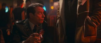 Movie still from “First Blood” (1982), directed by Ted Kotcheff – A man in a suit and tie smoking a cigarette and holding a drink; Close Up shot, Over the shoulder angle