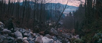 Movie still from “First Blood” (1982), directed by Ted Kotcheff – A man sitting on a pile of wood in the middle of a forest; Extreme Wide shot, High angle
