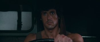 Movie still from “First Blood” (1982), directed by Ted Kotcheff – A man with a bandana on his head driving a car; Close Up shot, Over the shoulder angle