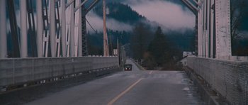 Movie still from “First Blood” (1982), directed by Ted Kotcheff – A car driving down a street near a bridge; Extreme Wide shot, High angle
