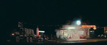 Movie still from “First Blood” (1982), directed by Ted Kotcheff – A man riding a motorcycle in front of a gas station at night; Extreme Wide shot, High angle