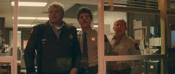 Movie still from “First Blood” (1982), directed by Ted Kotcheff – A group of men standing next to each other in front of a window; Medium shot, Low angle