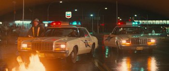 Movie still from “First Blood” (1982), directed by Ted Kotcheff – A couple of police cars driving down a street at night; Wide shot, Low angle