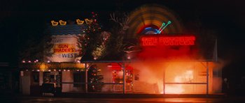 Movie still from “First Blood” (1982), directed by Ted Kotcheff – A neon sign that is lit up at night time; Extreme Wide shot, Low angle