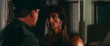 Movie still from “First Blood” (1982), directed by Ted Kotcheff – A person with a face paint; Close Up shot, Over the shoulder angle