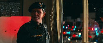 Movie still from “First Blood” (1982), directed by Ted Kotcheff – A man in a military uniform standing in front of a window; Medium shot, Over the shoulder angle