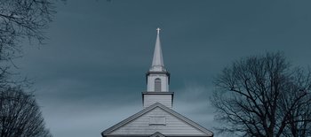 Movie still from “First Reformed” (2017), directed by Paul Schrader – A church steeple with a cross on top of it; Extreme Wide shot, Low angle