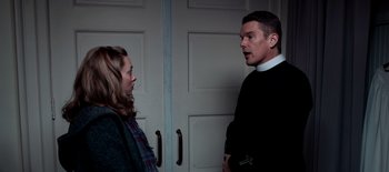 Movie still from “First Reformed” (2017), directed by Paul Schrader – A man and a woman standing next to each other in front of a door; Medium shot, Low angle