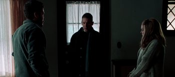 Movie still from “First Reformed” (2017), directed by Paul Schrader – A man standing in front of a window in a dark room; Medium shot, Over the shoulder angle