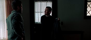 Movie still from “First Reformed” (2017), directed by Paul Schrader – A man holding a jacket in front of a window; Medium shot, Low angle