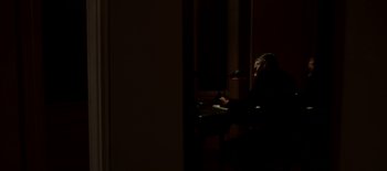 Movie still from “First Reformed” (2017), directed by Paul Schrader – A person sitting at a table in a dark room; Medium shot, High angle