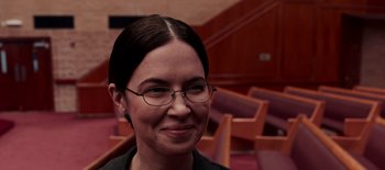 Movie still from “First Reformed” (2017), directed by Paul Schrader – A woman wearing glasses standing in front of a row of chairs; Close Up shot, Over the shoulder angle