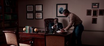 Movie still from “First Reformed” (2017), directed by Paul Schrader – Two men are sitting at a desk in an office; Medium shot, High angle