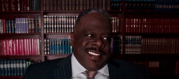 Movie still from “First Reformed” (2017), directed by Paul Schrader – A man in a suit and tie in front of a book shelf; Close Up shot, High angle