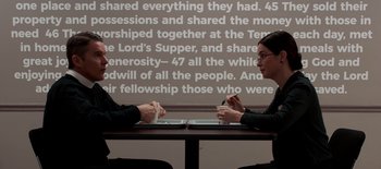 Movie still from “First Reformed” (2017), directed by Paul Schrader – Two people are sitting at a table with plates of food in front of them; Medium shot, Over the shoulder angle