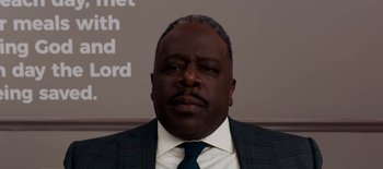 Movie still from “First Reformed” (2017), directed by Paul Schrader – A man in a suit and tie in front of a sign; Close Up shot, Low angle