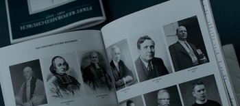 Movie still from “First Reformed” (2017), directed by Paul Schrader – An open book with a picture of a man in a suit and tie; Extreme Close Up shot, High angle