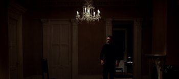 Movie still from “First Reformed” (2017), directed by Paul Schrader – A man standing in front of a chandelier in a dark room; Extreme Wide shot, Low angle