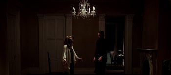Movie still from “First Reformed” (2017), directed by Paul Schrader – A man and a woman standing in front of chandeliers; Wide shot, Low angle