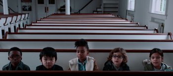 Movie still from “First Reformed” (2017), directed by Paul Schrader – A group of children sitting in a row of pews; Medium shot, High angle
