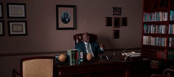 Movie still from “First Reformed” (2017), directed by Paul Schrader – A man sitting at a desk in front of books; Medium shot, High angle