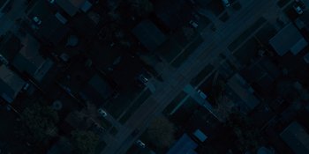 Movie still from “Five Nights at Freddy's” (2023), directed by Emma Tammi – An aerial view of a city street at night time; Extreme Wide shot, Overhead angle
