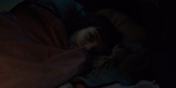 Movie still from “Five Nights at Freddy's” (2023), directed by Emma Tammi – A young girl is laying in bed with a teddy bear; Close Up shot, High angle
