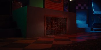 Movie still from “Five Nights at Freddy's” (2023), directed by Emma Tammi – A metal grate on the side of a building; Wide shot, High angle