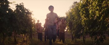 Movie still from “Flamin' Hot” (2023), directed by Eva Longoria – A group of people walking through a field at sunset; Wide shot, Low angle