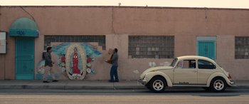 Movie still from “Flamin' Hot” (2023), directed by Eva Longoria – A man walking down the street carrying a box; Wide shot, Low angle