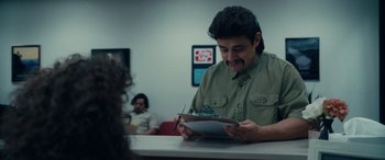 Movie still from “Flamin' Hot” (2023), directed by Eva Longoria – A man in a green shirt is looking at a clipboard; Medium shot, Over the shoulder angle