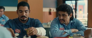 Movie still from “Flamin' Hot” (2023), directed by Eva Longoria – Two men sitting at a table with a green apple; Close Up shot, Over the shoulder angle