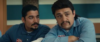 Movie still from “Flamin' Hot” (2023), directed by Eva Longoria – A couple of men sitting next to each other on top of a couch; Close Up shot, Over the shoulder angle