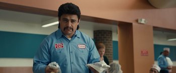 Movie still from “Flamin' Hot” (2023), directed by Eva Longoria – A man in a blue shirt holding some food; Close Up shot, Low angle