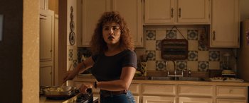Movie still from “Flamin' Hot” (2023), directed by Eva Longoria – A woman standing in a kitchen holding a knife in her hand; Medium shot, Over the shoulder angle