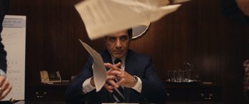 Movie still from “Flamin' Hot” (2023), directed by Eva Longoria – A man sitting at a table with papers in front of him; Medium shot, Over the shoulder angle