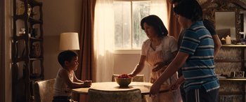 Movie still from “Flamin' Hot” (2023), directed by Eva Longoria – A woman and a child at a table with a bowl of fruit; Medium shot, Low angle
