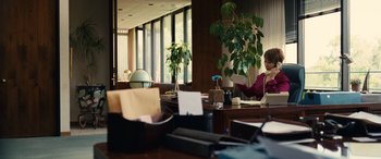 Movie still from “Flamin' Hot” (2023), directed by Eva Longoria – A woman sitting at a desk in an office setting; Medium shot, High angle