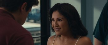 Movie still from “Flamin' Hot” (2023), directed by Eva Longoria – A woman smiling at the camera in front of a window; Close Up shot, Over the shoulder angle