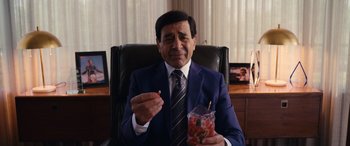 Movie still from “Flamin' Hot” (2023), directed by Eva Longoria – A man in a suit and tie sitting in an office chair; Close Up shot, High angle