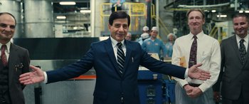 Movie still from “Flamin' Hot” (2023), directed by Eva Longoria – A man wearing a suit and tie standing in a factory; Medium shot, Over the shoulder angle