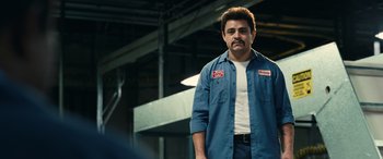 Movie still from “Flamin' Hot” (2023), directed by Eva Longoria – A man standing in a warehouse wearing a work shirt; Medium shot, Low angle