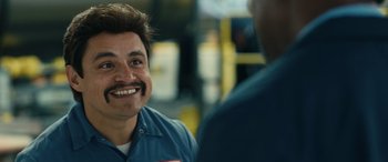 Movie still from “Flamin' Hot” (2023), directed by Eva Longoria – A man with a beard and mustache smiling for a picture; Close Up shot, Over the shoulder angle