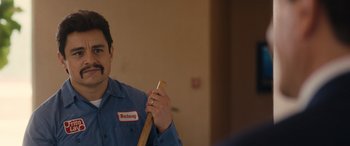 Movie still from “Flamin' Hot” (2023), directed by Eva Longoria – A man holding a baseball bat in a room; Close Up shot, Over the shoulder angle