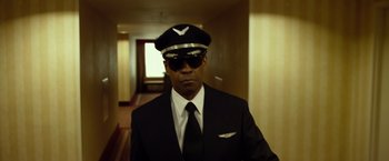 Movie still from “Flight” (2012), directed by Robert Zemeckis – A man in a suit and tie wearing a hat and sunglasses; Medium shot, Low angle
